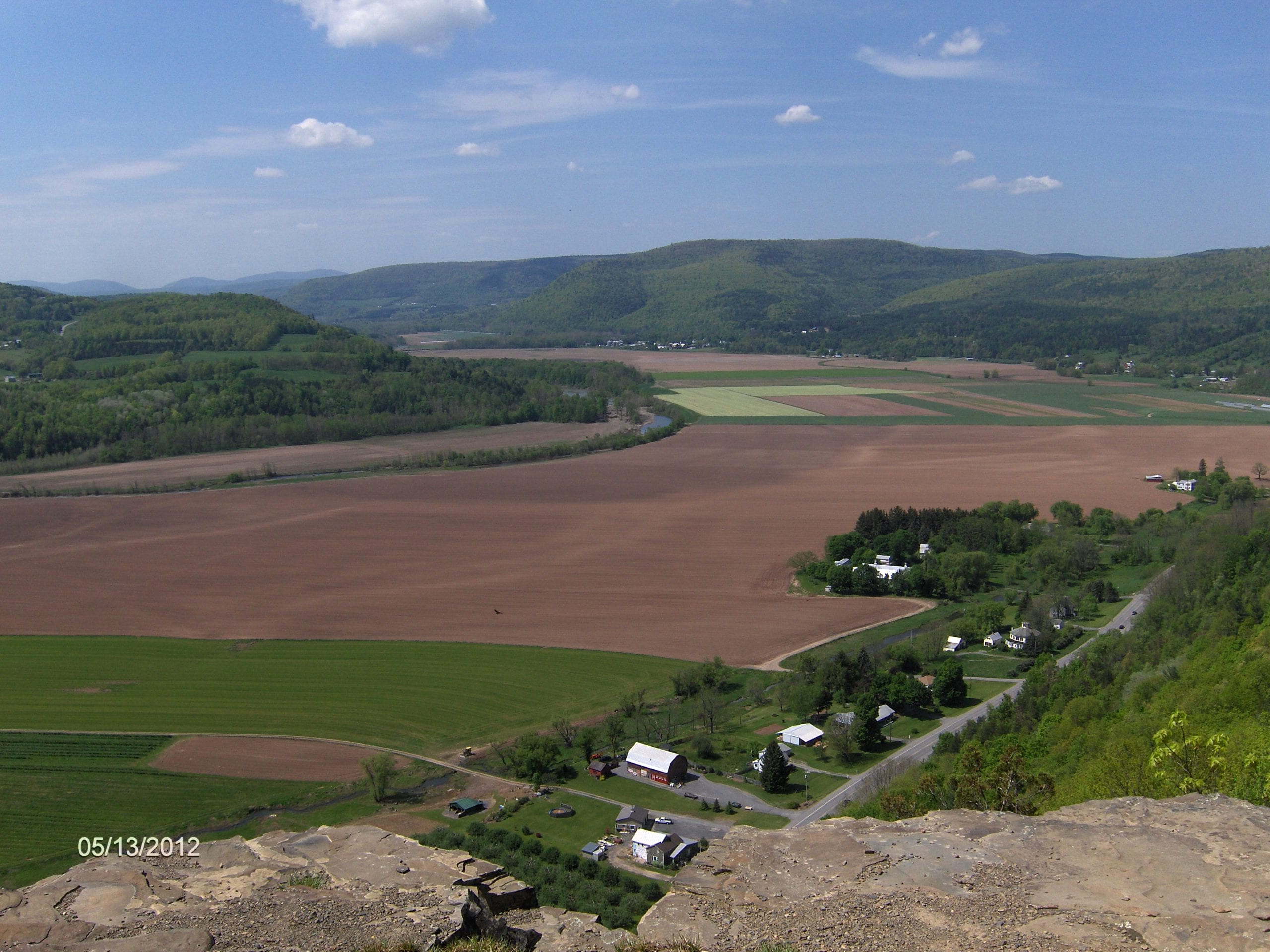 photograph of Vroman's Nose, a mountain, in the distance beyond a farmed field