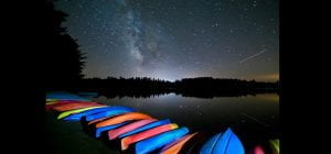 photograph of canoes on shore at night by Mark Bowie