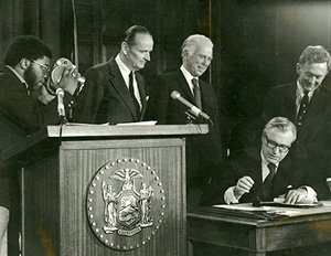 Governor Nelson Rockefeller signs the Adirondack Park Agency's Private Land Use and Development Plan into law in 1973. Behind him stand APA Chairman Richard W. Lawerence (left), Perry Duryea (center) and Bernard C. Smith (Right), Chairman of the New York State Senate's Environmental Conservation Committee.