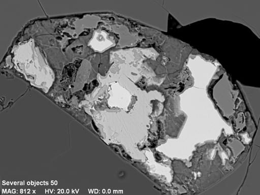 This is a weathered sulfide crystal in a Norwegian eclogite, surrounded by silicates. In the backscattered electron image the weathered sulfide has a variety of irregular patches with different shades of gray. In the X-ray map (put cursor over the image), quartz and feldspar show up as blue and purple, respectively. Iron hydroxide is red, pyrite is orange, chalcopyrite is greenish-yellow, and a nickel sulfide is light-green. Initially the sulfide was probably a pyrrhotite solid solution.